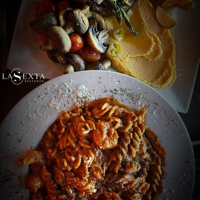 Setas salteadas y pasta en mesa servida.